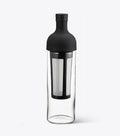 Hario clear glass bottle with black cap and interior filter on a white background