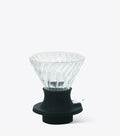 Clear glass coffee dripper with black base on a white background