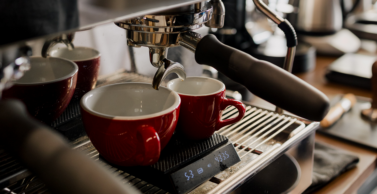Espresso machine with red cups being filled with coffee